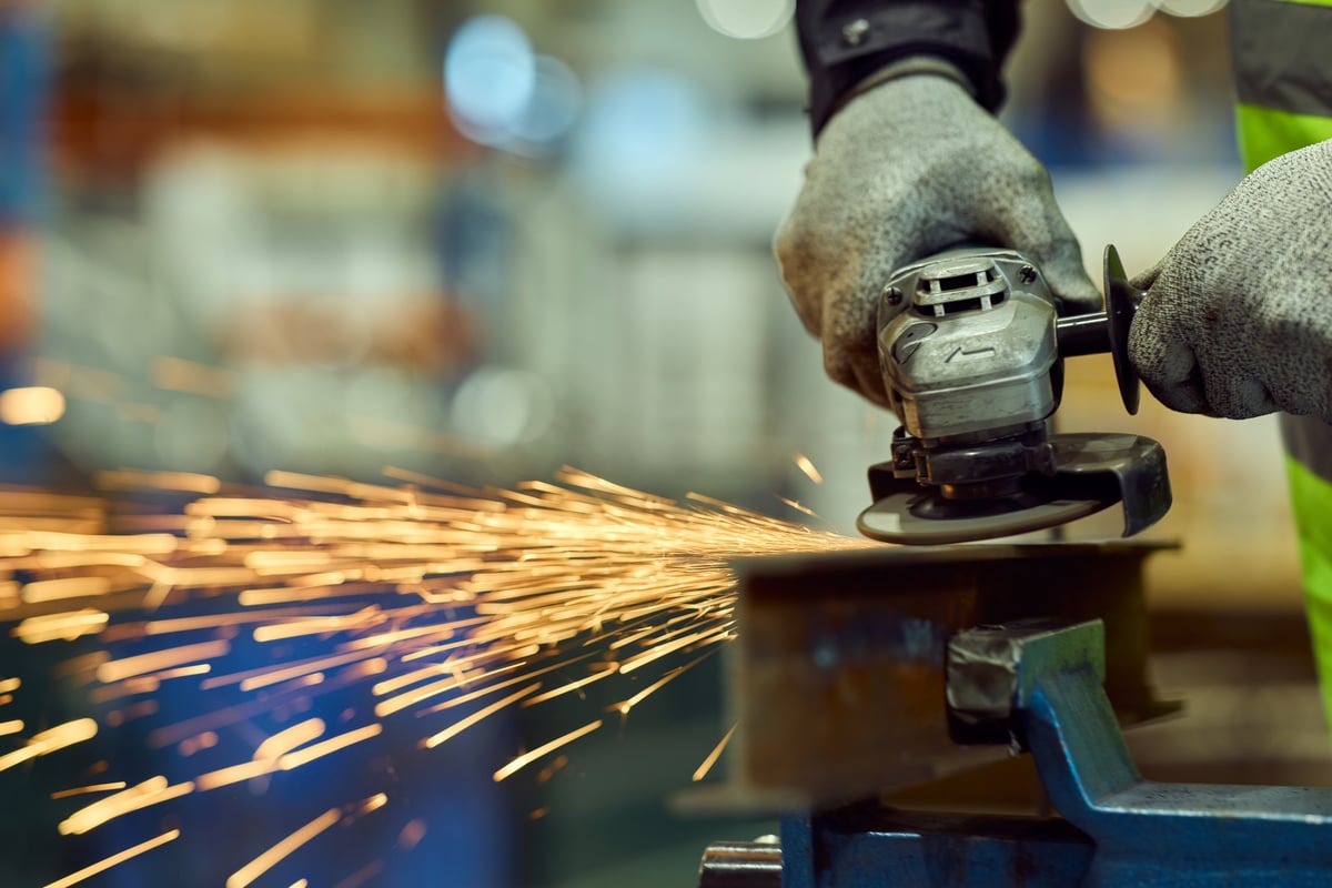 Trabajador puliendo metal protegido con guantes y equipo de seguridad