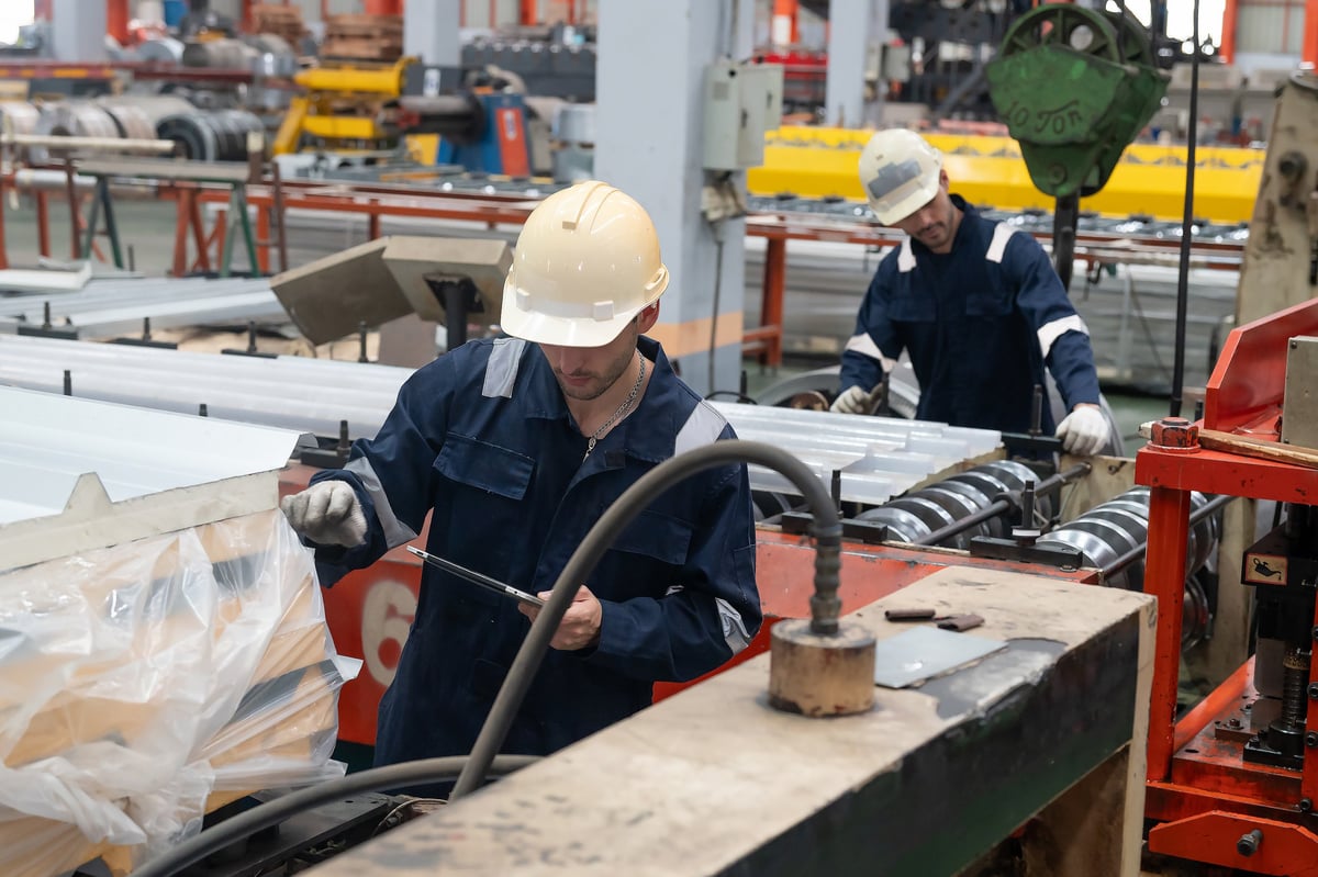 Trabajadores inspeccionando planchas metálicas en la línea de producción